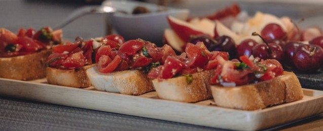 closeup of bruschetta on plate with grapes and apples in the bacground