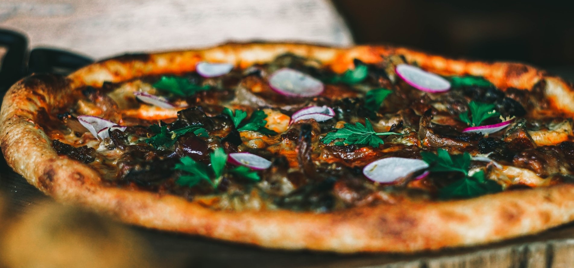 closeup of duck, radishes and arugula on a pizza