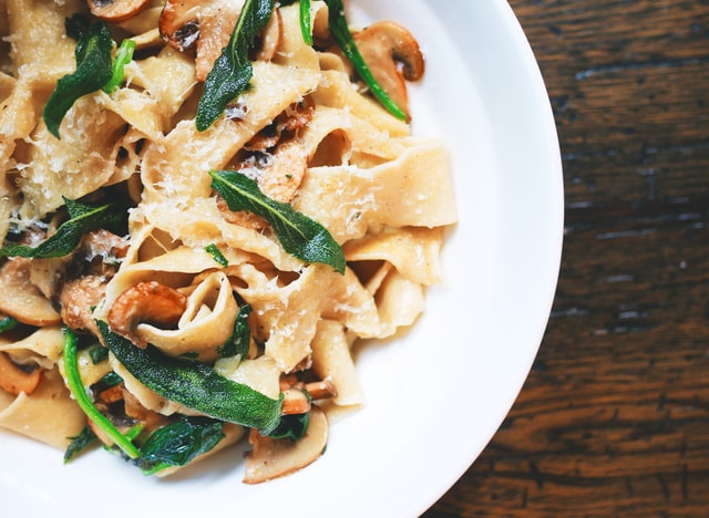 closeup image of mushroom spinach pappardelle on a white plate